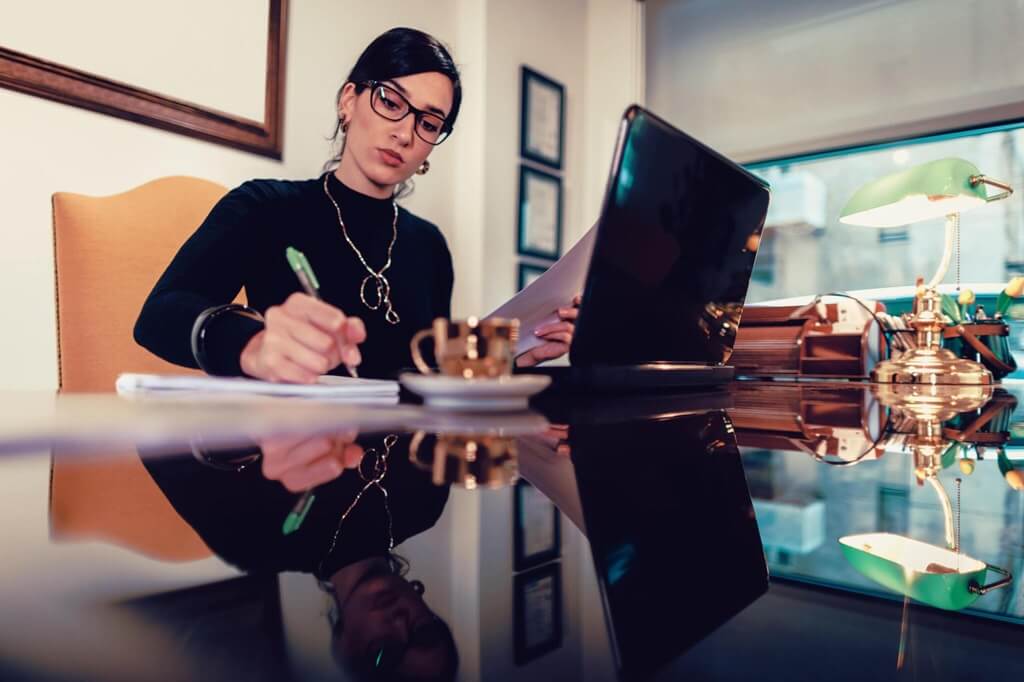 A woman wearing glasses is seen at a desk, working on a laptop as part of the Advanced Certificate Programme in Data and Public Policy Analytics.